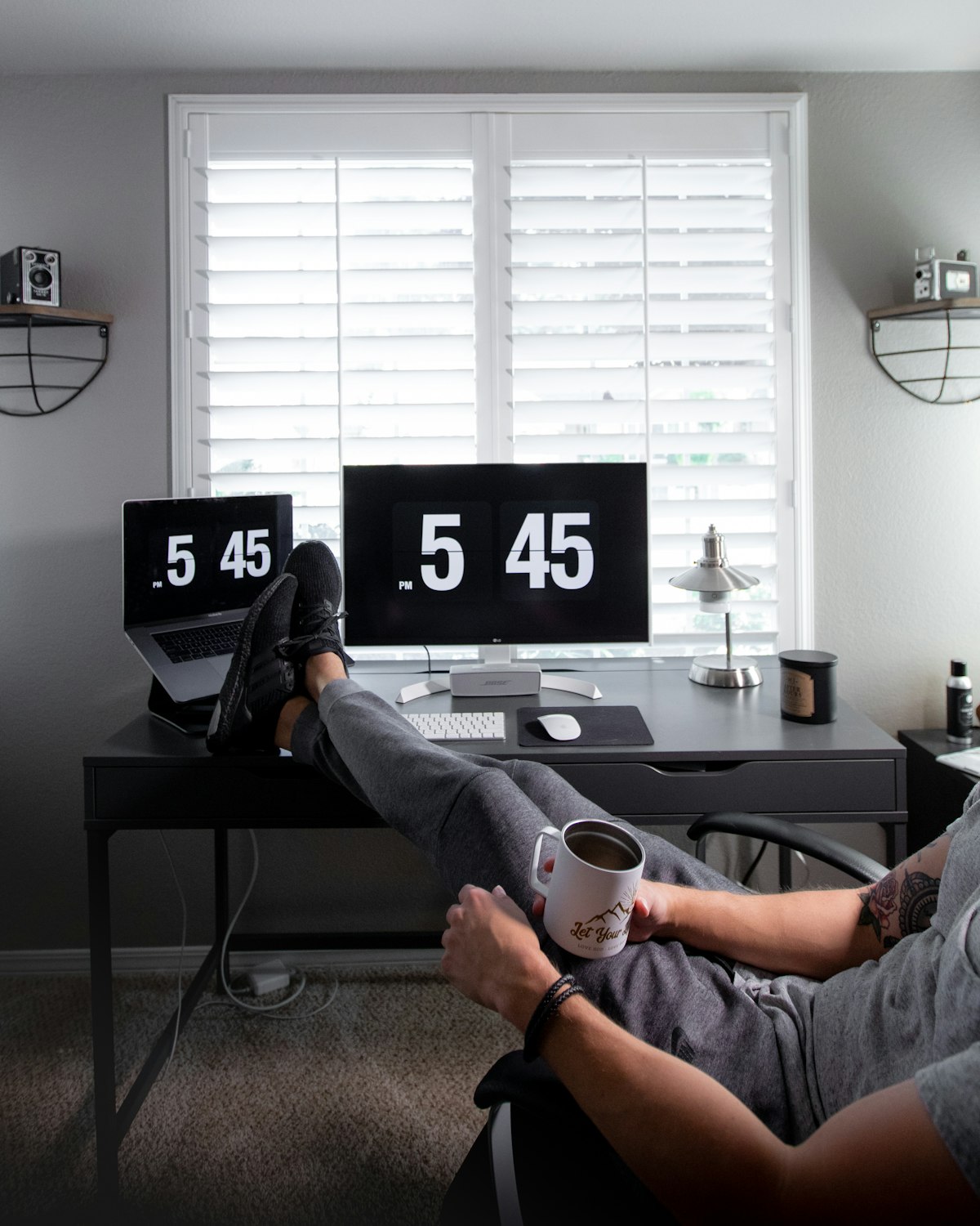 Person working at a home desk with feet propped up, illustrating the kind of relaxed foot position an angled footrest is designed to support