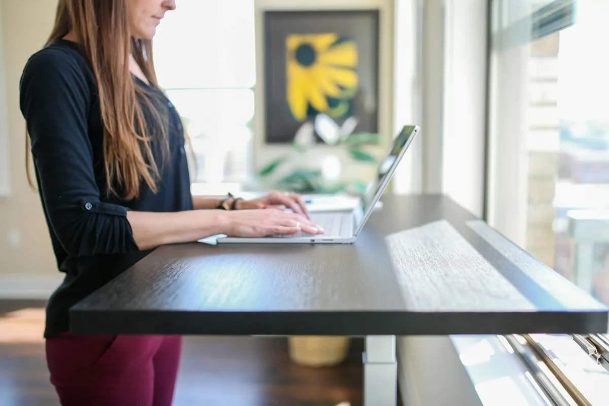 Woman sitting at a desk using a laptop with a keyboard positioned at elbow height