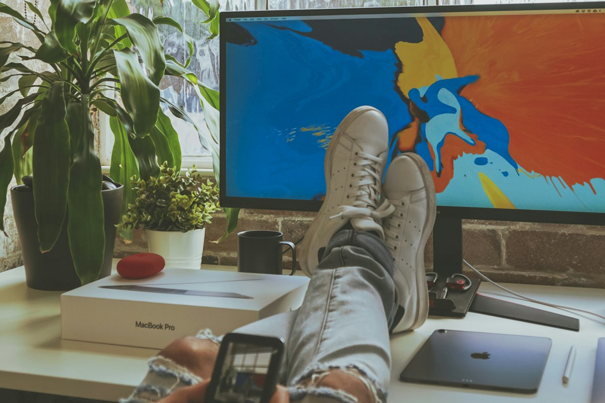 Close view of bare feet resting near a desk, illustrating the kind of low, close footrest position ergonomics guidance recommends