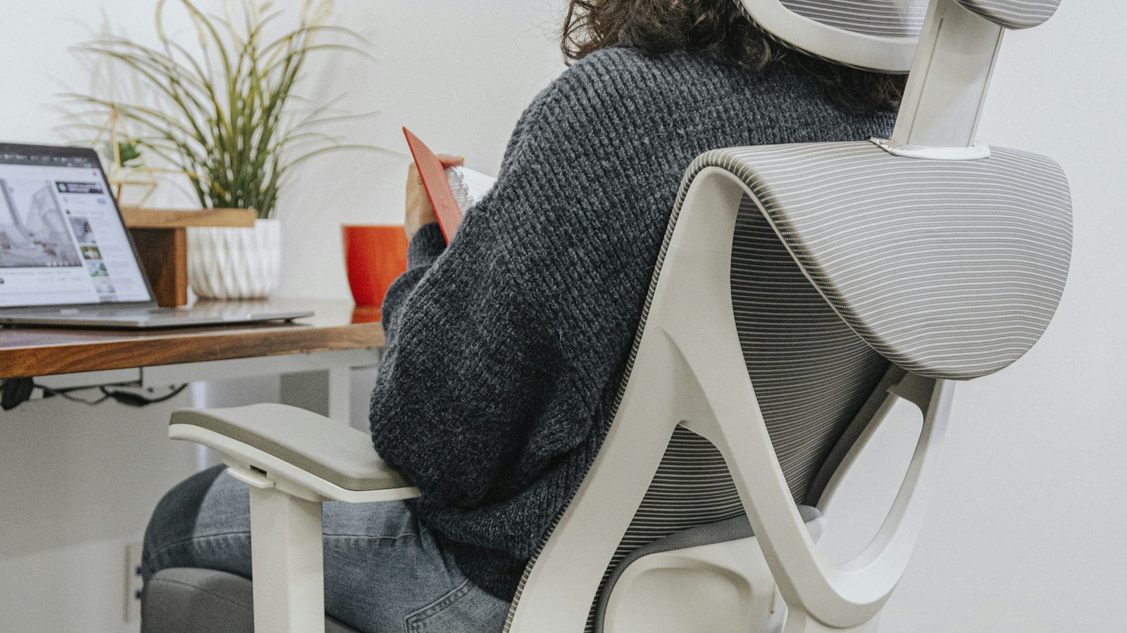 Woman sitting at a home office desk working at her computer, the kind of setup where footrest posture mistakes go unnoticed