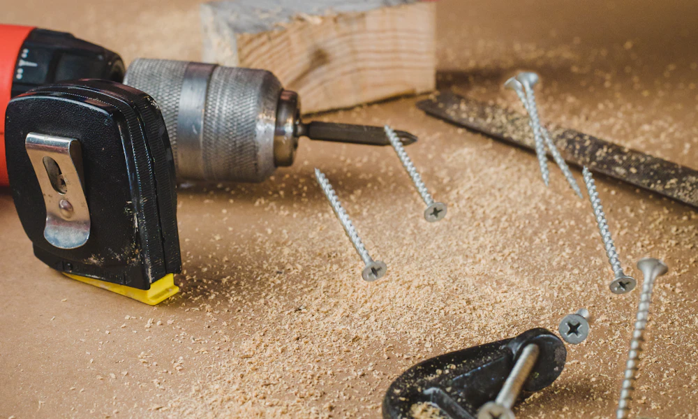 Cordless drill on a workbench with screws, representing the drilling required to install a track-mounted keyboard tray