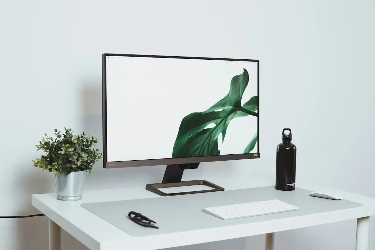 Close-up of a white laminate desk surface with a monitor in a minimal office setup