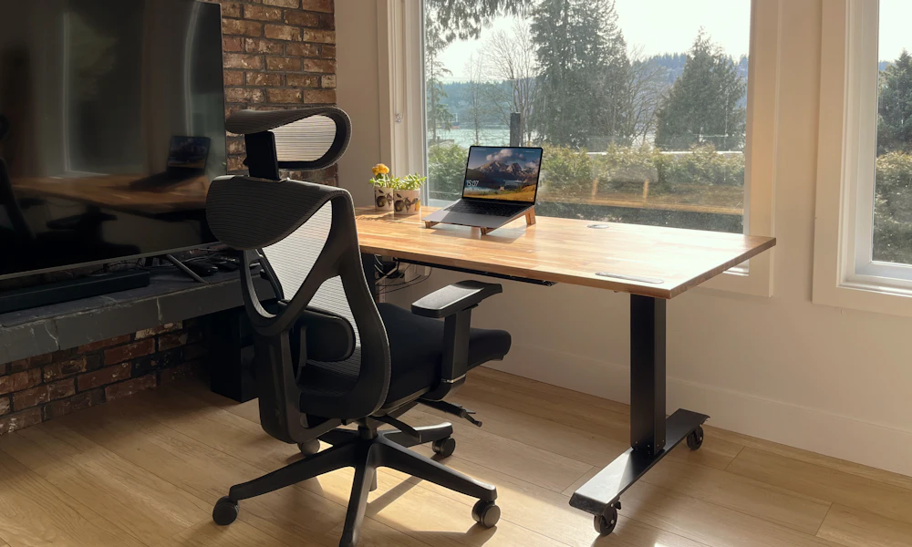 Signs Your Laptop Stand Is the Wrong Height 2 Laptop on a wooden desk in front of a bright window in a home office workspace