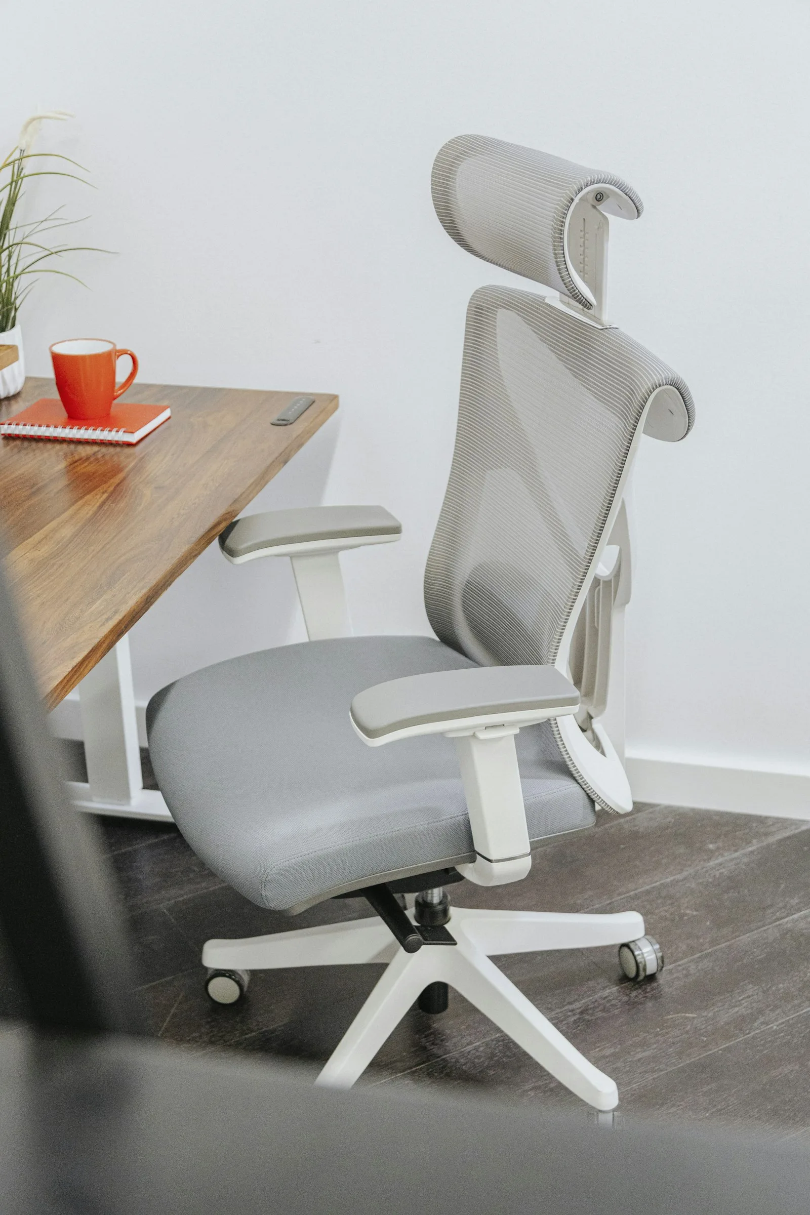 Memory Foam vs Inflatable Lumbar Cushion: Which Is Better? 1 Gray ergonomic office chair at a wooden desk, the kind of chair where a lumbar cushion gets added later
