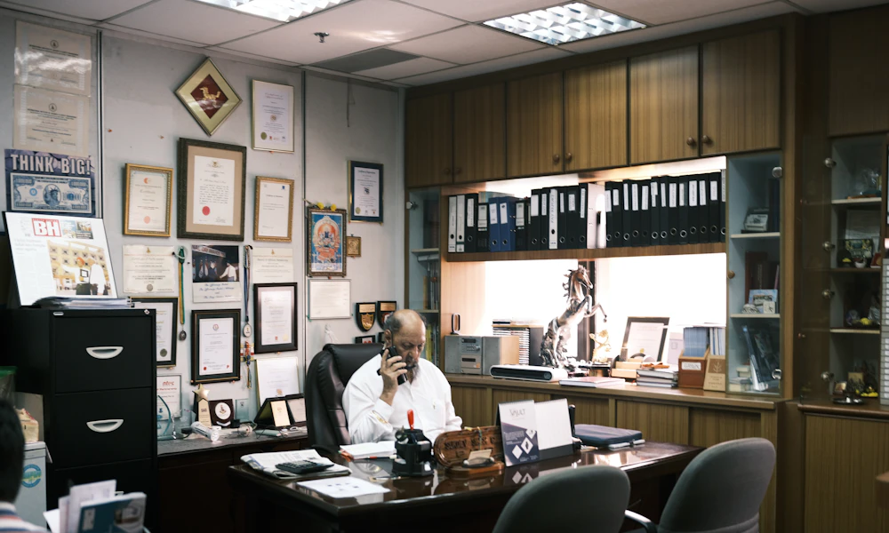 Person sitting in a black office rolling chair at a desk, showing the back and lumbar area of the chair