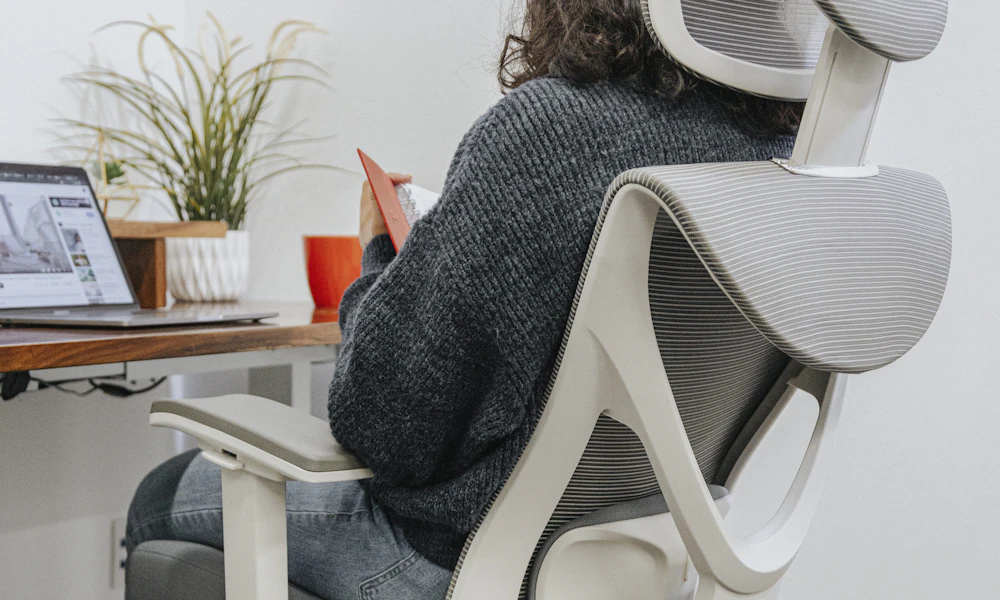 Person sitting at a desk in an ergonomic office chair with visible lumbar support