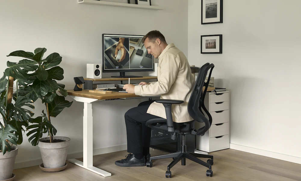 How to Sit Properly in an Office Chair for Back Pain 2 Person sitting at a desk workstation in front of a computer, illustrating a typical office chair and desk setup