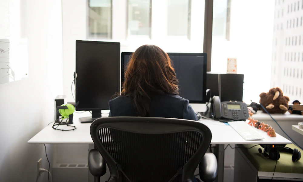 Kneeling Chair vs Standard Office Chair for Back Pain 2 Person seated at a desk with a desktop computer setup, a typical full workday seating scenario