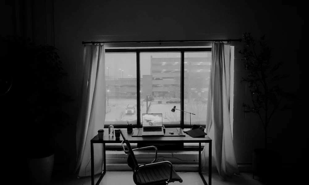 Office desk positioned in front of a sunlit window, illustrating direct sunlight exposure that speeds up mesh fiber breakdown