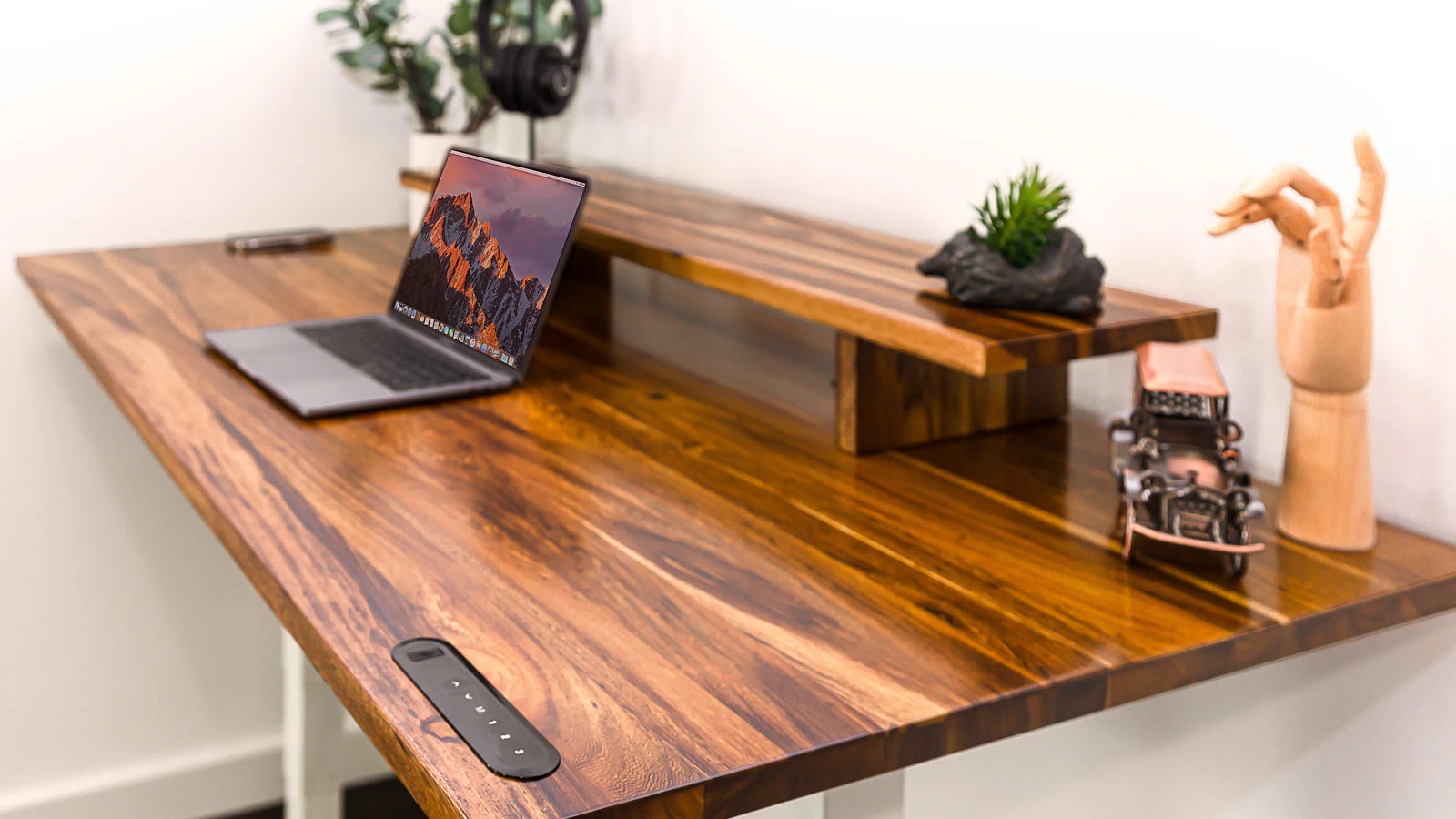 Wooden standing desk in a bright home office with a laptop and desk accessories, set up at standing height