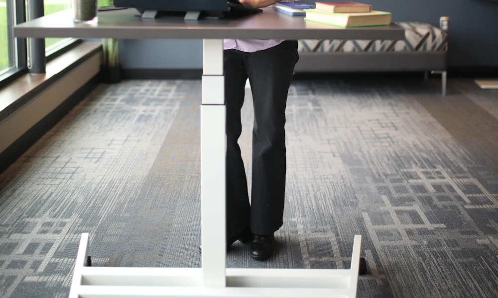 Woman working on a laptop at a standing desk in a modern office setting