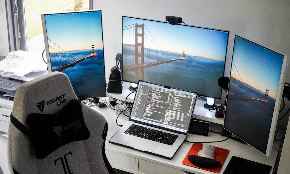 Desk with two monitors and a laptop arranged for a dual-screen workspace