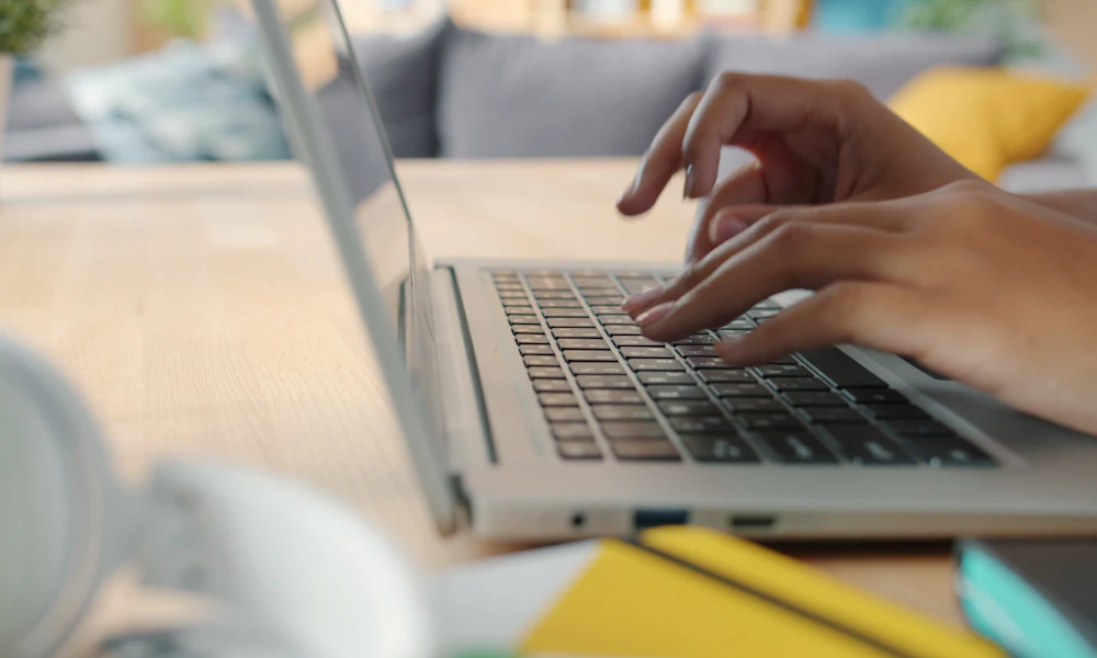 Does an Ergonomic Keyboard Slow Down Your Typing Speed? 2 Hands typing on a laptop keyboard at a desk during a work session